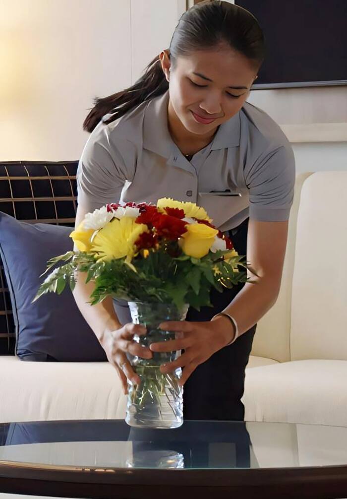 Woman arranging a vase of flowers on ship suites